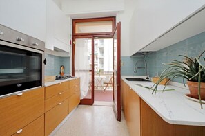 A modern kitchen with wooden cabinets, a built-in oven, and a marble countertop. - Appartamento luminoso a San Pietro (Roma)