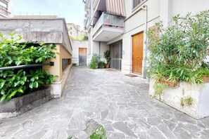 A narrow stone-paved alleyway with a small garden area on the left and a balcony on the right. - Appartamento luminoso a San Pietro (Roma)