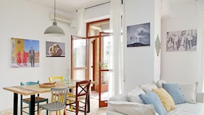 Una habitación con comedor, un sofá blanco y obras de arte en las paredes.