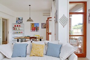 A cozy living room with a sofa, a dining table, and a bookshelf. - Appartamento luminoso a San Pietro (Roma)