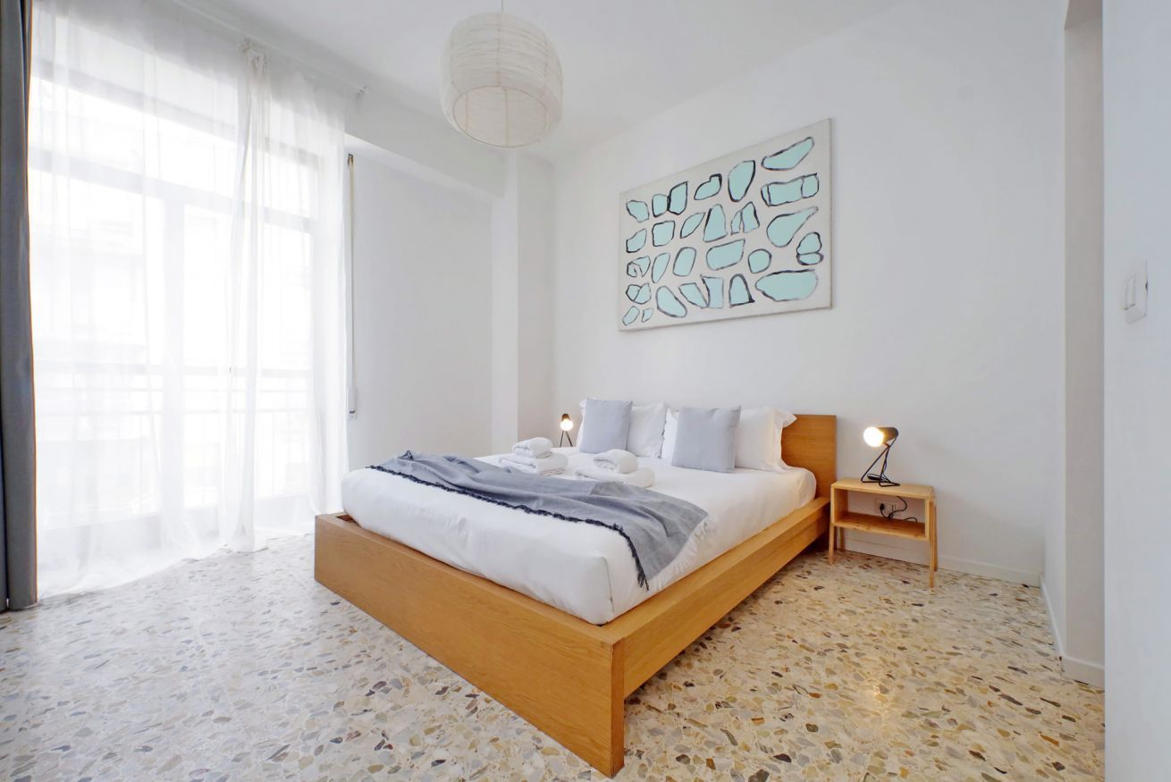 A bedroom with a bed, bedside tables, and a wall art piece.
