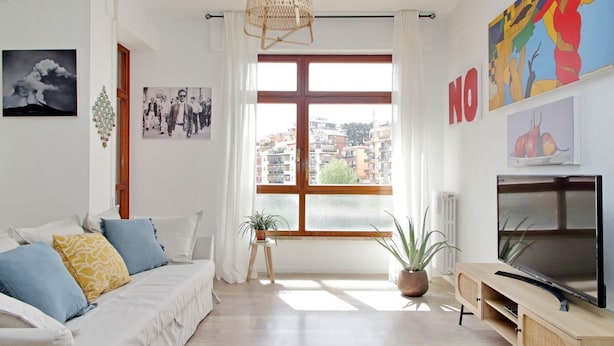 Una sala de estar moderna con sofá, televisión y ventana grande.