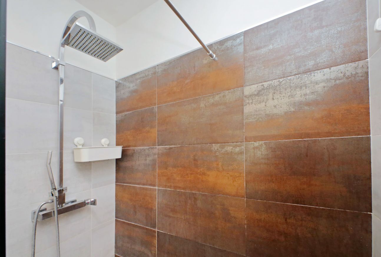 A shower area with a rain showerhead and a handheld shower attachment.