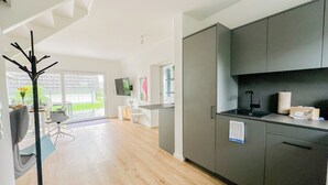 Eine moderne Küche mit grauen Schränken, einer schwarzen Arbeitsplatte und Blick ins Freie.