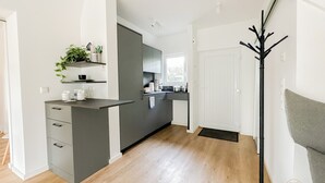 Eine moderne Küche mit grauen Schränken, einer Arbeitsplatte und einem Fenster. Eine Tür führt in einen anderen Raum.