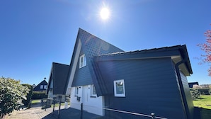 Ein Wohnhaus mit einem steilen Satteldach, einer sichtbaren Haustür und einem kleinen Fenster.