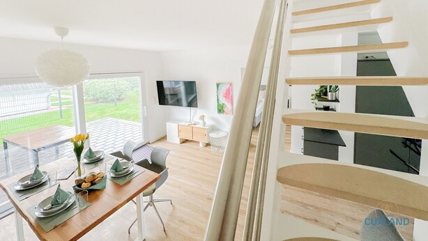 Ein modernes Interieur mit Essbereich, Treppe und Blick ins Freie.