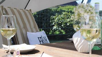 A table with two wine glasses, a plate with food, a pillow with text, and a bottle of wine.