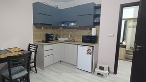 A compact kitchen with a dining table, chairs, a refrigerator, a microwave, and cabinets. - Perfect 1-bedroom apartment in adorable Pamporovo for your getaway (Pamporovo)