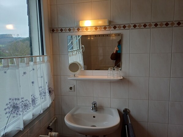 A bathroom with a sink, mirror, and window. - Room “Double Room 3” with Shared Terrace, Garden, and Wi-Fi (Kirchhundem)
