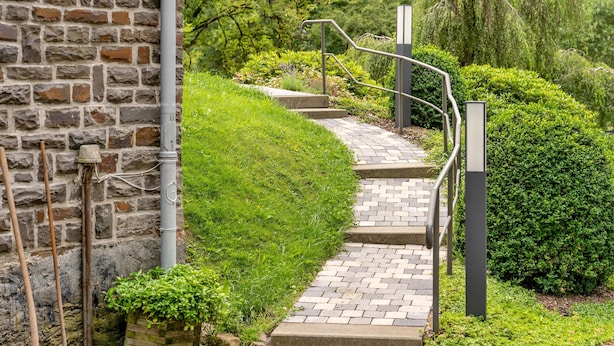 A stone wall, a brick pathway, metal railings, and green hedges. - Room “Double Room 3” with Shared Terrace, Garden, and Wi-Fi (Kirchhundem)