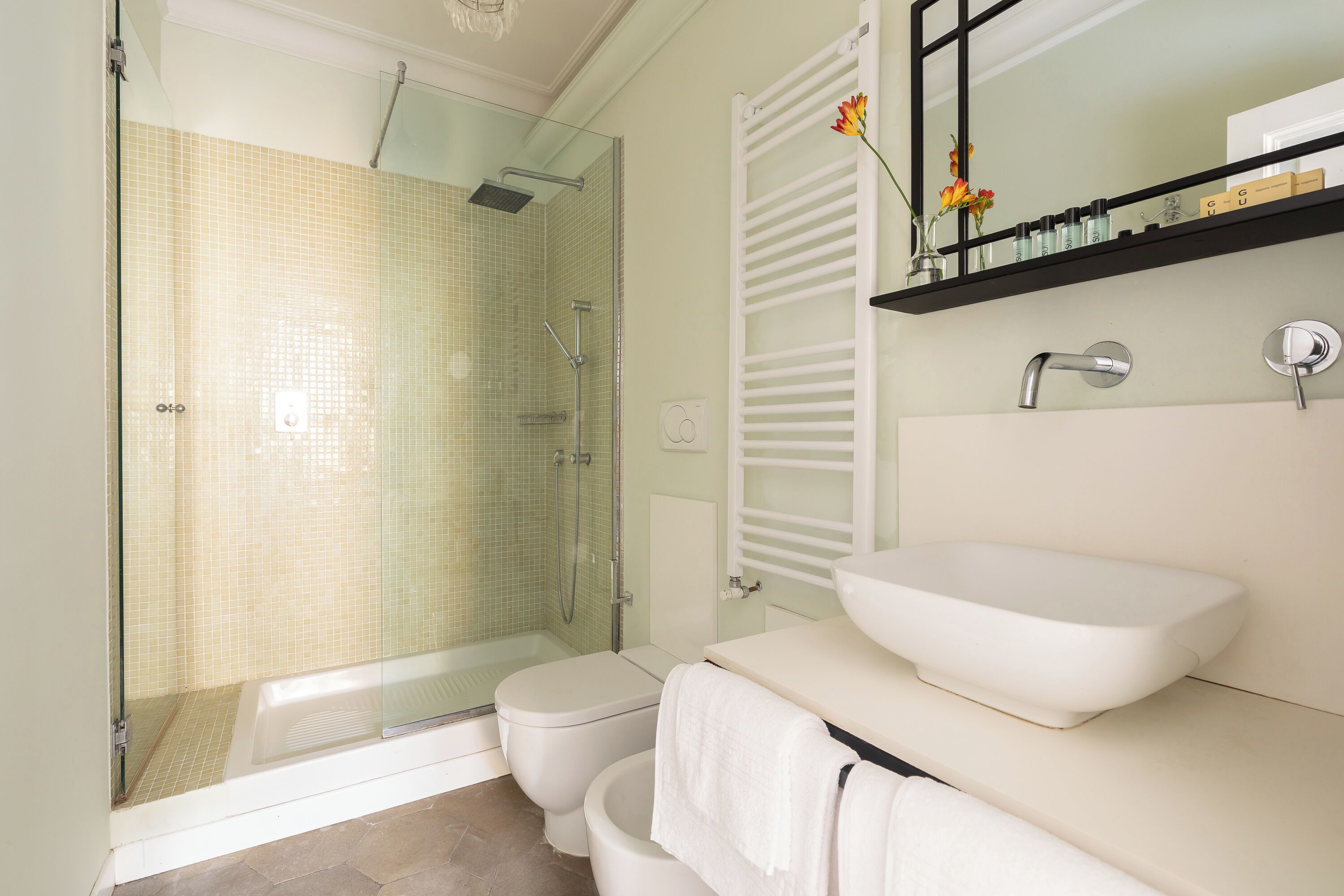 A modern bathroom with a glass-enclosed shower, a white sink, and a toilet.