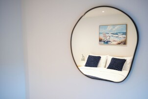 Un dormitorio con cama, dos almohadas, una mesita de noche y un cuadro de una playa.