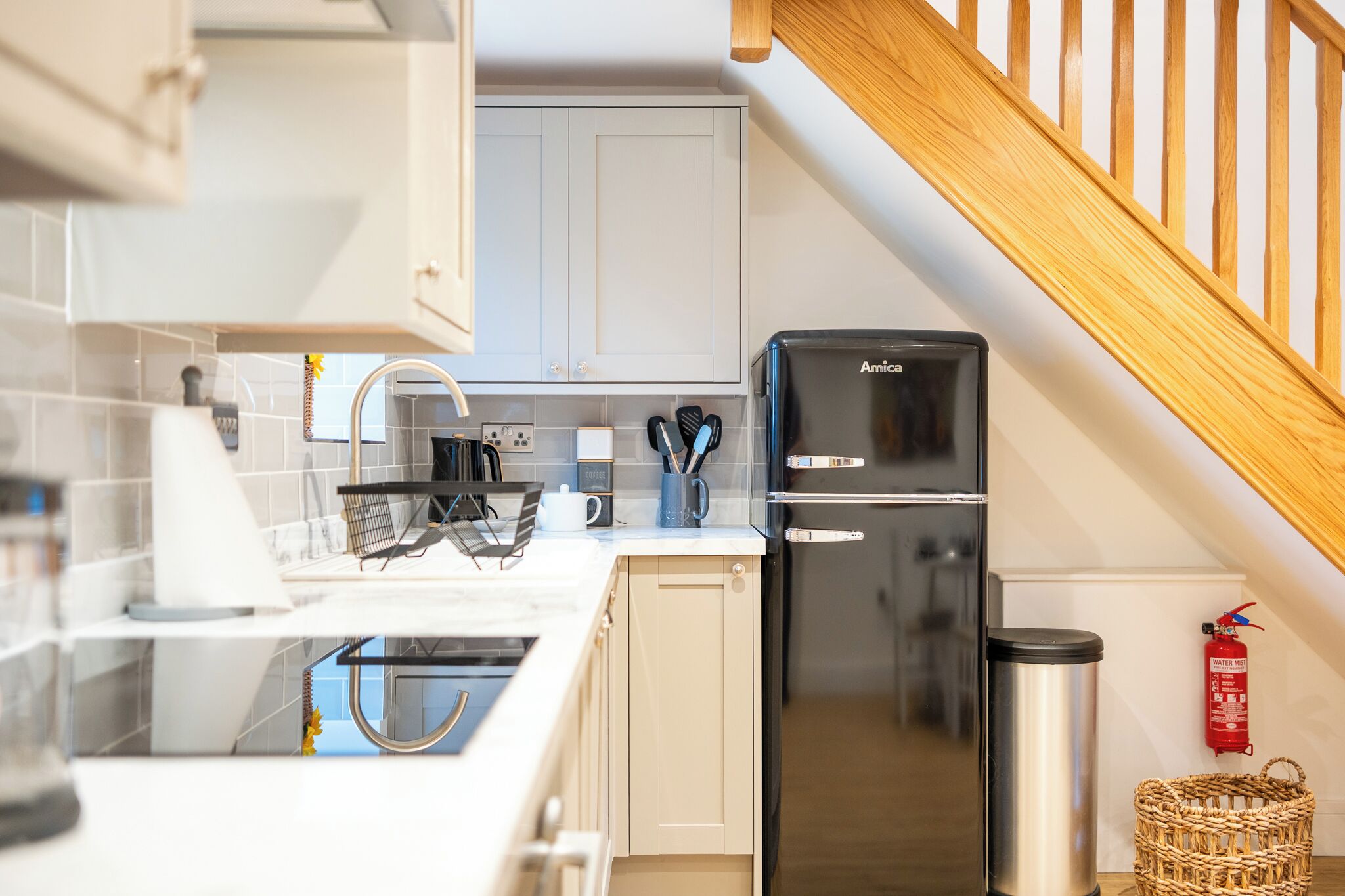 A modern kitchen with white cabinets, a black refrigerator, and a stainless steel sink.