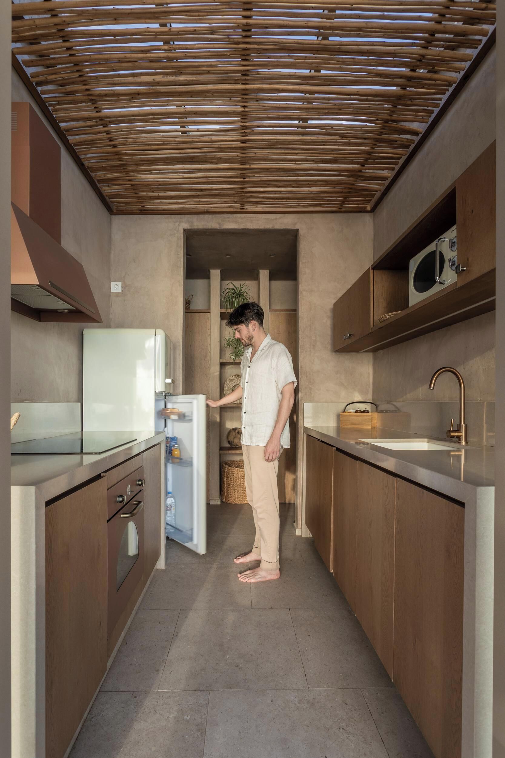 A modern kitchen with a built-in refrigerator, wooden cabinets, a stainless steel sink, and a bamboo ceiling.