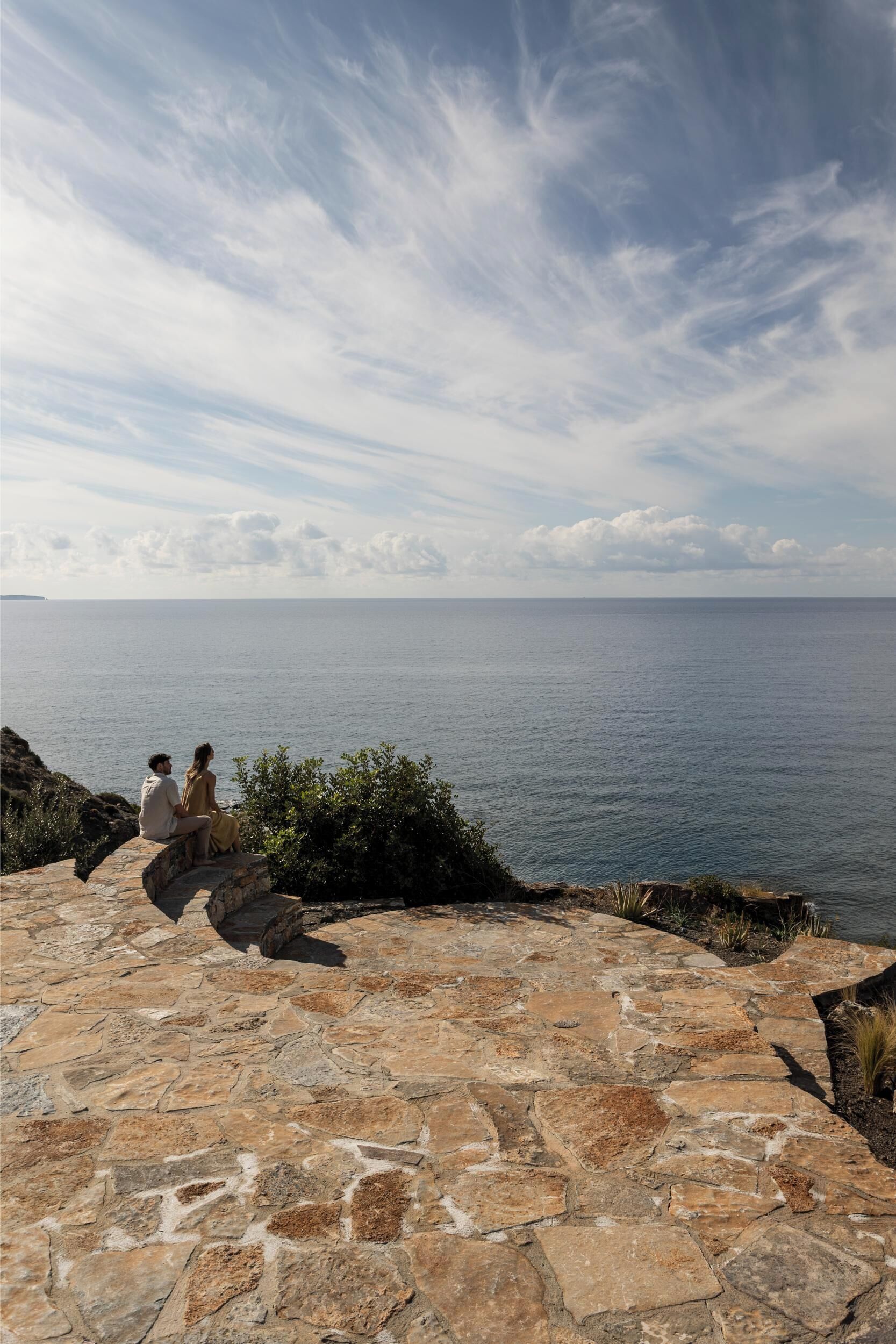 A stone pathway leading to a seating area overlooking a body of water.