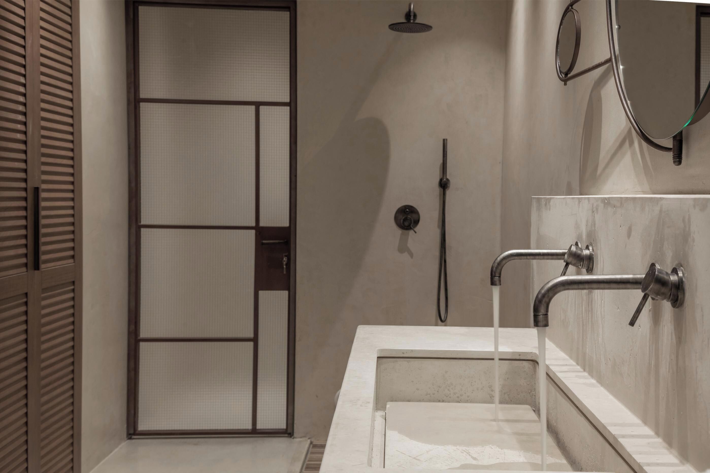 Ein modernes Badezimmer mit großem Spiegel, Dusche und Waschbecken mit fließendem Wasser.