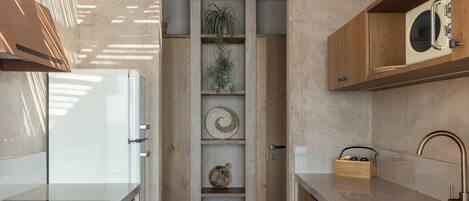 Una cocina moderna con armarios de madera, horno empotrado y microondas. Hay una repisa con plantas y adornos.