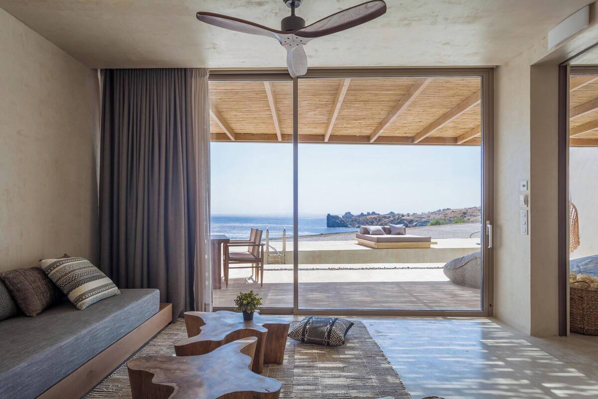 A modern living room with a large sliding glass door leading to a balcony with a view of the ocean.