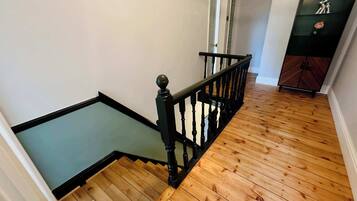 Una escalera de madera con barandillas negras que lleva a un rellano.