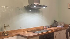 Eine Küche mit einer Edelstahl-Dunstabzugshaube, einer Holzauskleidetheke, einem eingebauten Backofen und einer Spüle mit zwei Becken.