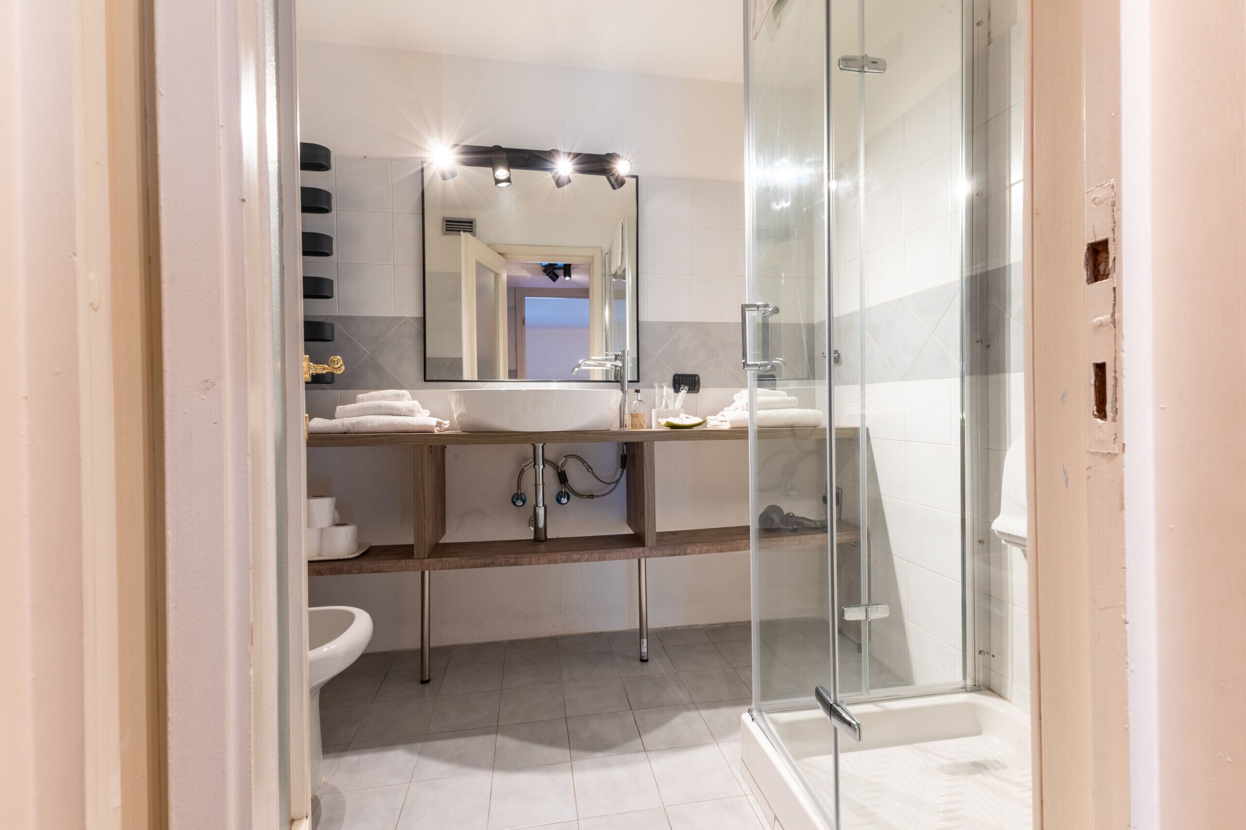 Un baño moderno con cabina de ducha de vidrio, tocador con espejo y lavamanos.