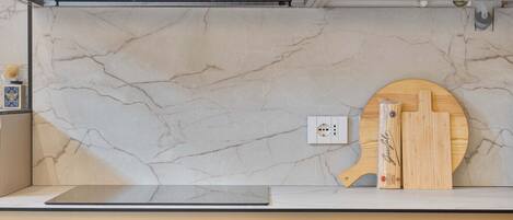 A kitchen with a marble backsplash, a wooden cutting board, and a knife block.