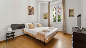 A modern hotel room with a large bed, a bedside table with a lamp, a TV, and a window with curtains. - Central Milan Apartment - 10 min Duomo (Milan)
