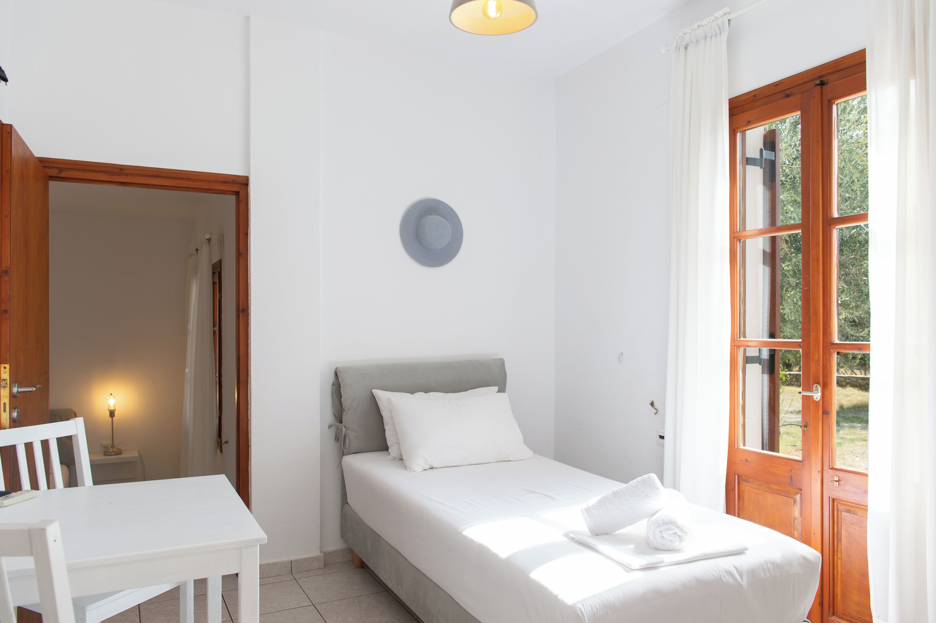 A small, clean room with a bed, a table, and a window.
