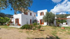 A white building with wooden shutters, a patio with outdoor furniture, and a view of the surrounding landscape. - Blue Fish (Sifnos)