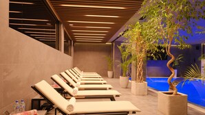 A modern indoor pool area with lounge chairs and potted plants. - Zamindor Resort (Zaamin)