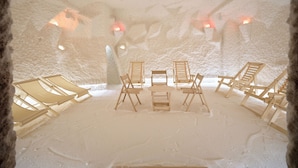 An ice hotel room with wooden chairs and tables, ice walls, and warm lighting. - Zamindor Resort (Zaamin)
