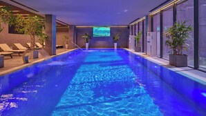 An indoor swimming pool with a blue-lit water feature, lounge chairs, and potted plants. - Zamindor Resort (Zaamin)