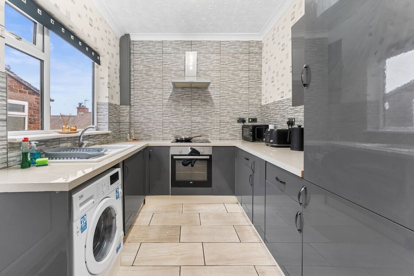 Una cocina compacta con lavadora, estufa y refrigerador.