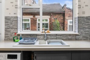 A kitchen with a window, a sink, and a dish rack. - Stoke Work Stay - Contractors & Families - Sleep 6 (Stoke-on-Trent)