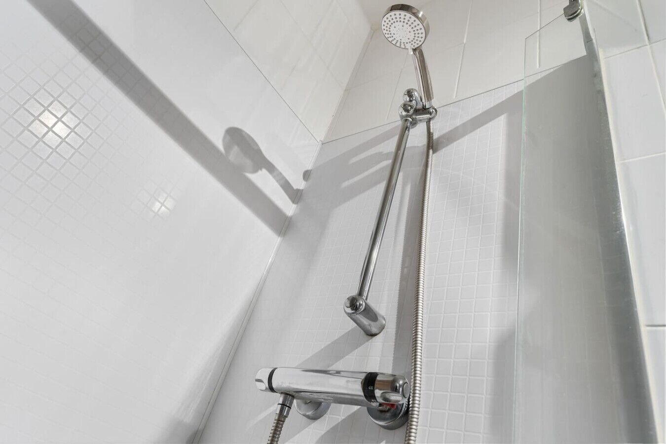 A shower with a handheld showerhead and a handheld faucet.