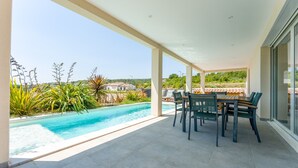 Un'area esterna coperta con piscina, sedie e tavolo.