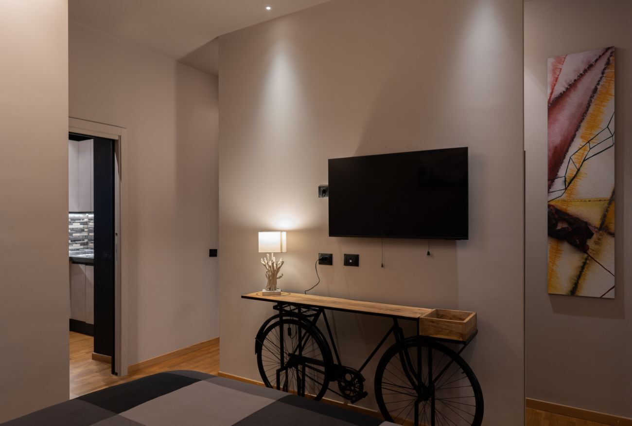 A modern interior with a mounted TV, a bicycle, and a minimalist console table.