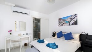 Ein modernes Schlafzimmer mit Bett, Schreibtisch und Dusche.