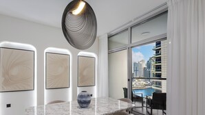 A modern dining area with a marble table, a vase, and three framed artworks on the wall. - LUX  The Sky Dubai Eye View Suite (Dubai)