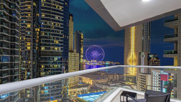 A high-rise building with a Ferris wheel in the background, a pool area, and a balcony with a railing. - LUX  The Sky Dubai Eye View Suite (Dubai)