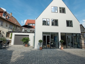 A modern two-story house with a garage, large glass doors, and potted plants. - Apartment '2 Riesling, 68qm' with Shared Terrace, Balcony and Wi-Fi (Iphofen)