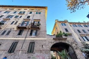 Um edifício de vários andares com varandas, fachada de pedra e entrada em arco.