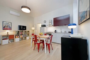 Eine moderne Küche mit Essbereich, ausgestattet mit einem Fernseher, Bücherregalen und einer Uhr.