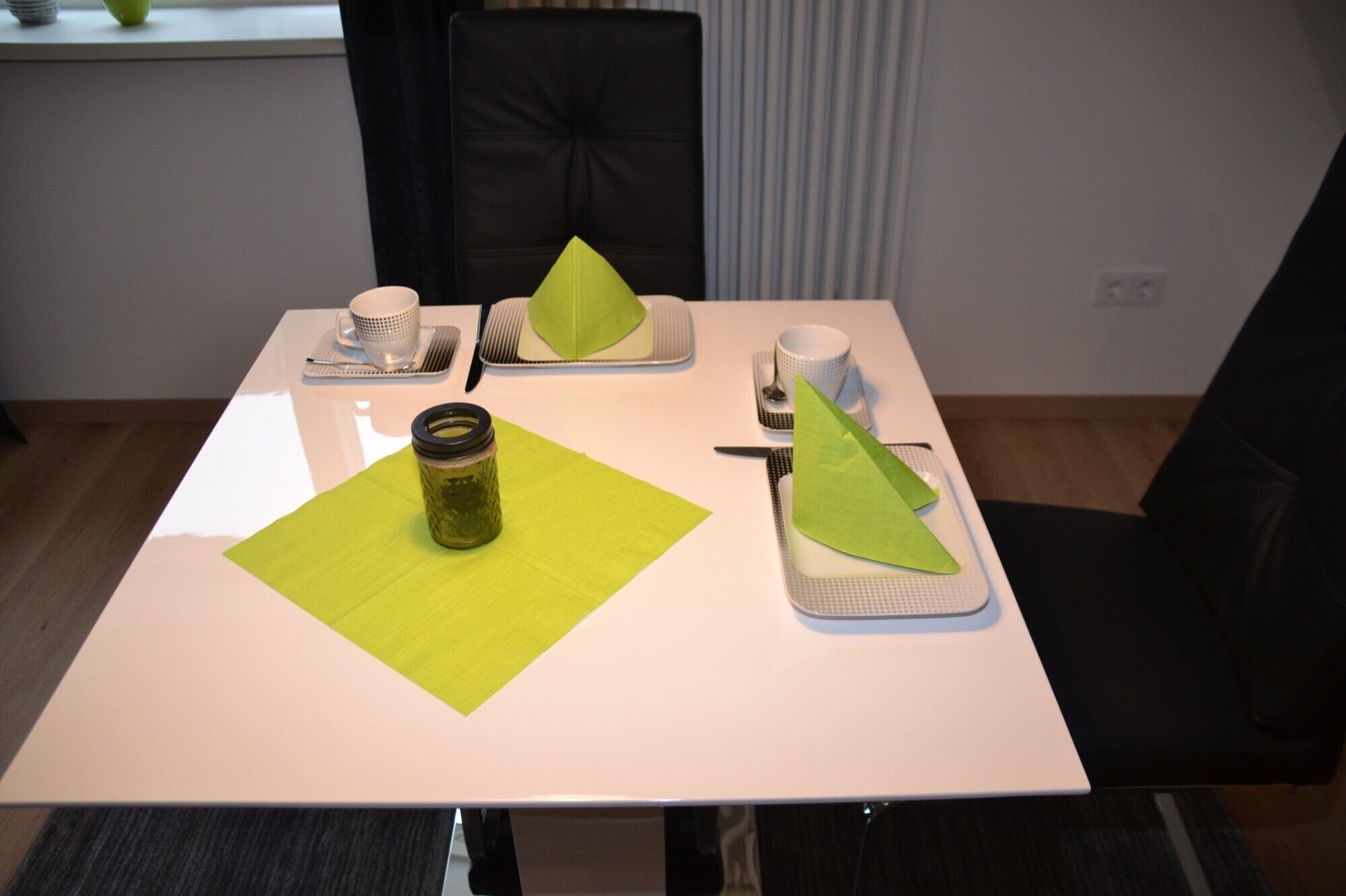 A dining table with a green placemat, a glass jar, and paper napkins.