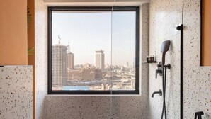 A modern bathroom with a large window, a shower, and a view of the cityscape. - StayBee - The Artists Gateway Room DownTown Cairo 5mins from Egyptian museum (cairo)
