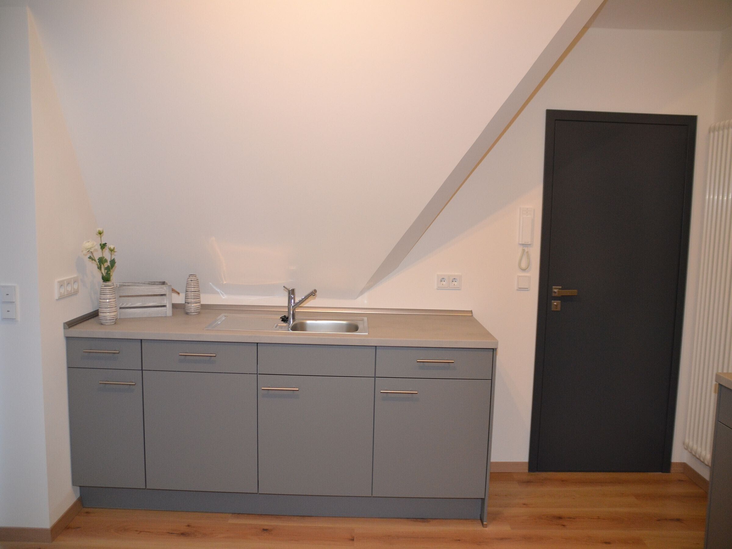 A kitchenette with a sink, cabinets, and a door.