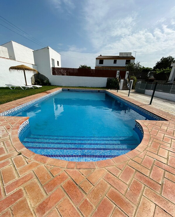 Una piscina con borde de azulejos, rodeada por un patio de ladrillo.