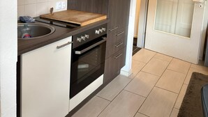 Une cuisine moderne avec des meubles de couleur sombre, une hotte de cuisine en acier inoxydable et un four encastré.