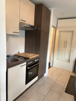 A modern kitchen with dark cabinetry, a stainless steel range hood, and a built-in oven. - Waldzeit Braunlage - WLAN - parking lot - terrace - at ground level (Braunlage)